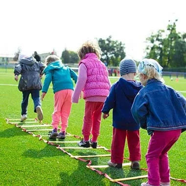 Ein Trainer von Strong Kids im Gespräch mit Eltern am Rande der Trainingsmatte.